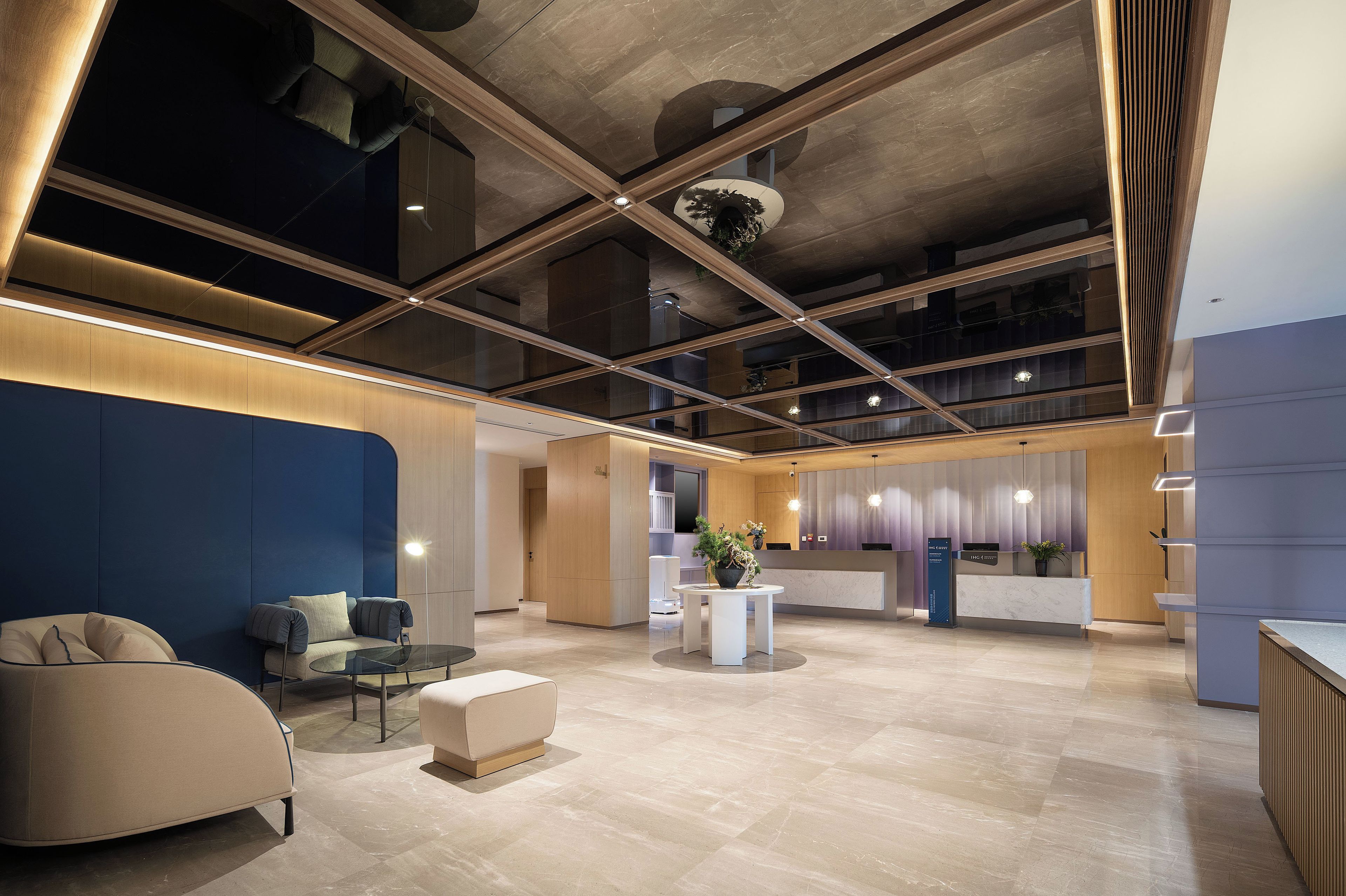 A spacious lobby with a reception desk, seating area, and a high ceiling with exposed beams.