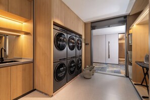 A modern hotel room with a built-in washer and dryer, a sink, and a small table with an iron. - Holiday Inn Express Huangshan Mountain South Gate By Ihg (Huangshan)