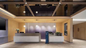 A modern reception area with a wooden reception desk, a vertical sign, and a ceiling with exposed beams and pendant lighting.
