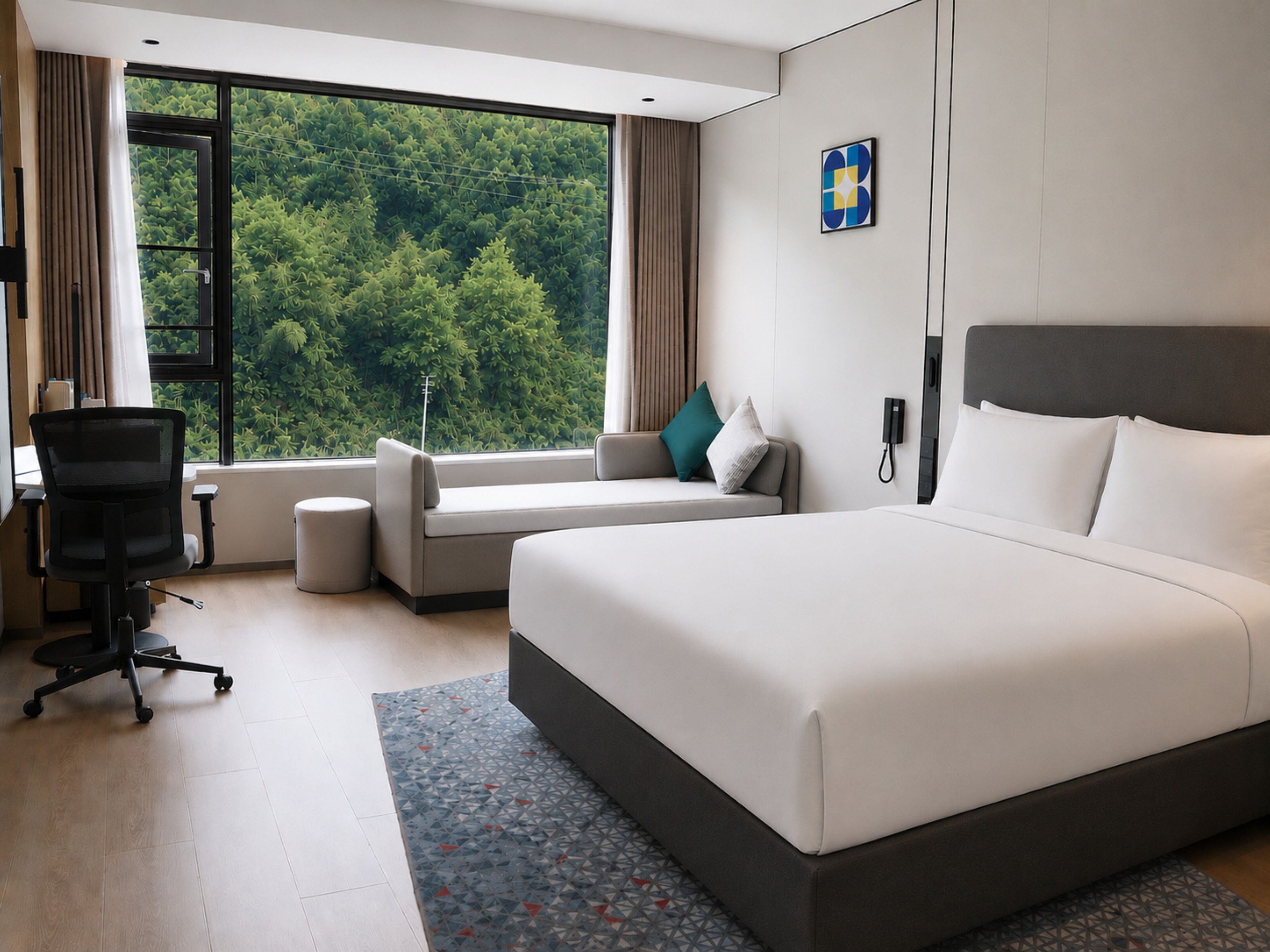 Habitación de hotel moderna con una cama grande, un sofá, un escritorio y vistas a zonas verdes por la ventana.