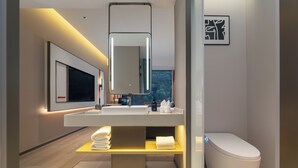 Une salle de bain moderne avec un grand miroir, un lavabo, des toilettes et un porte-serviettes.