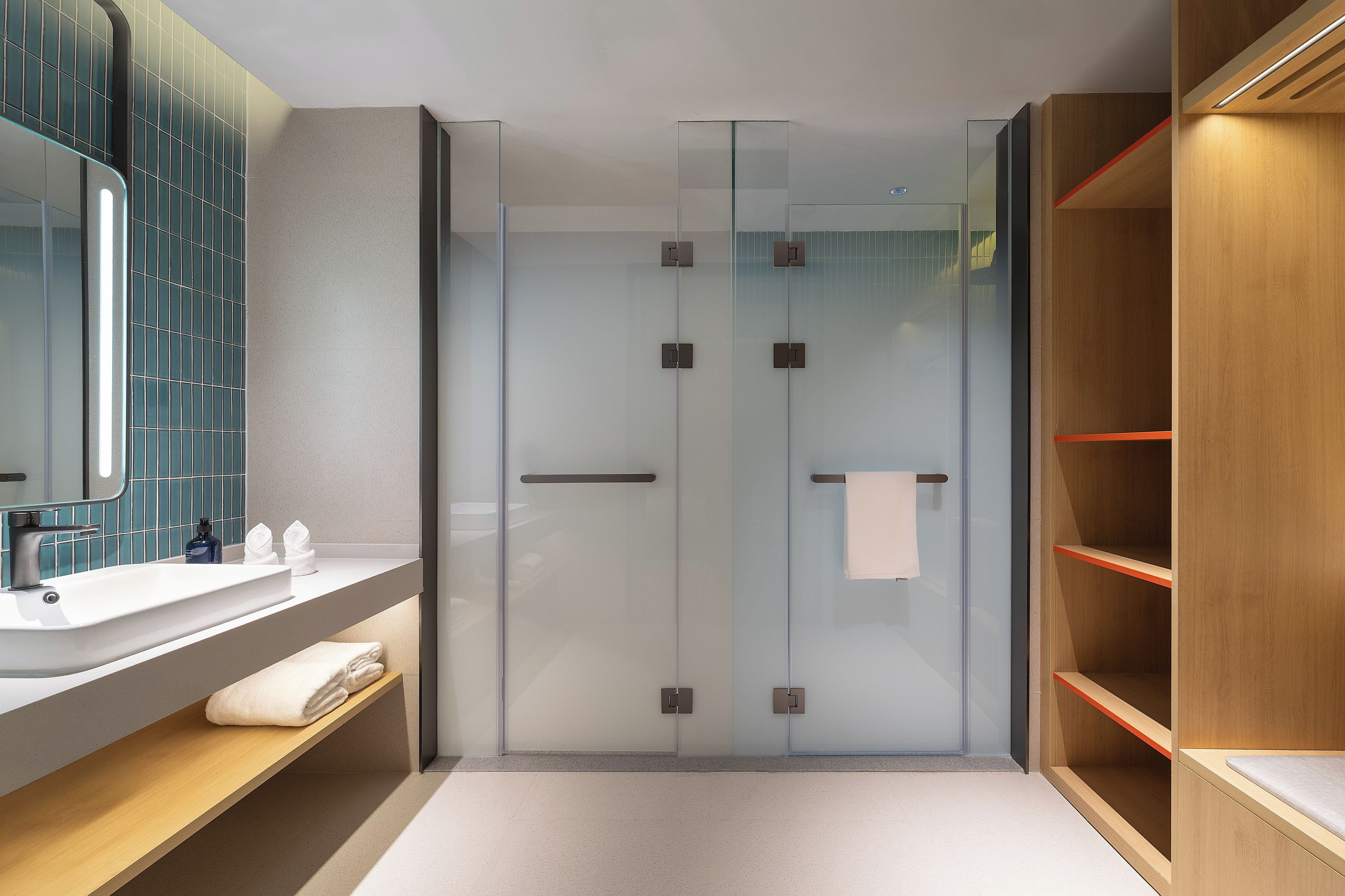 A modern bathroom with a glass shower enclosure, a wooden vanity with a sink, and a mirror.