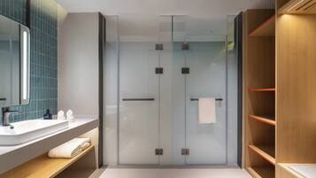 A modern bathroom with a glass shower enclosure, a wooden vanity with a sink, and a mirror.