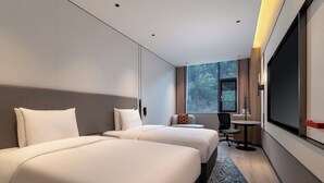 Une chambre d’hôtel avec deux lits, un bureau, une chaise et une grande fenêtre.