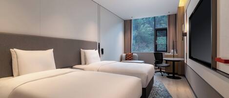Une chambre d’hôtel avec deux lits, un bureau, une chaise et une grande fenêtre.