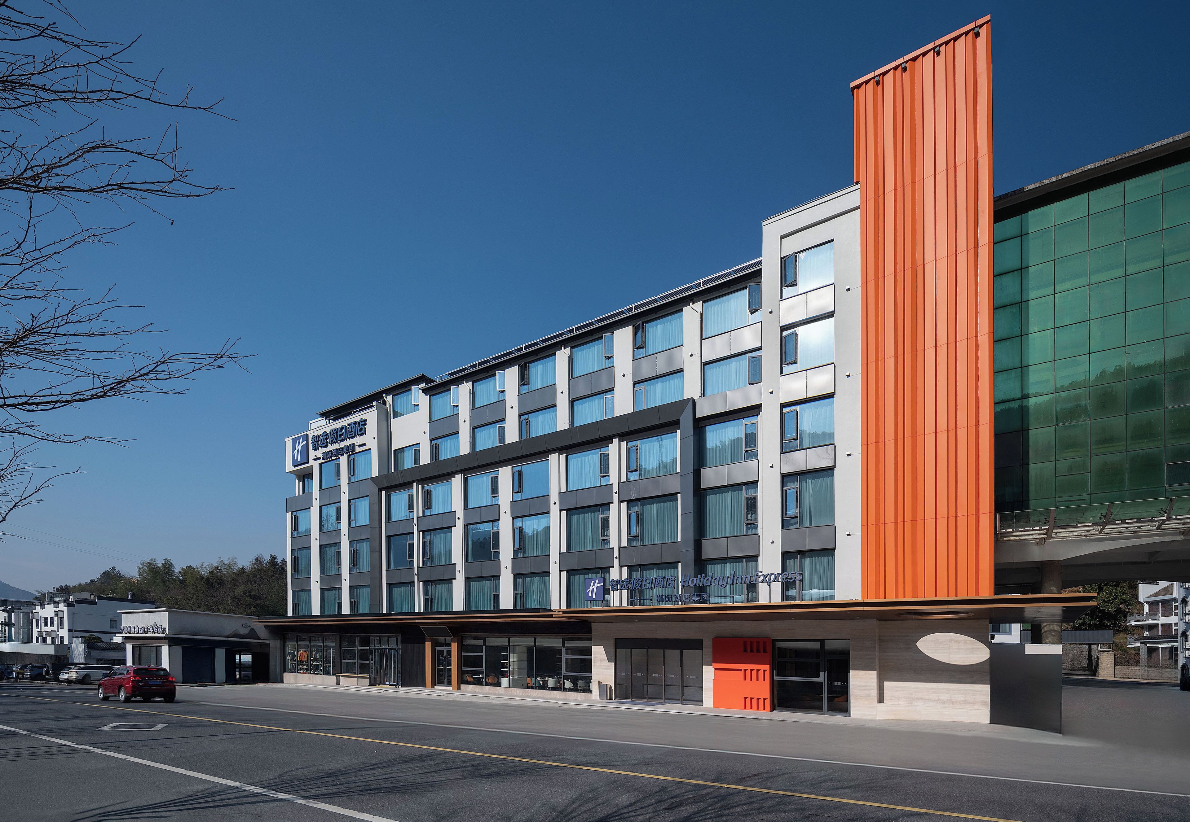 A modern hotel with a multi-story structure, large windows, and a prominent orange facade.