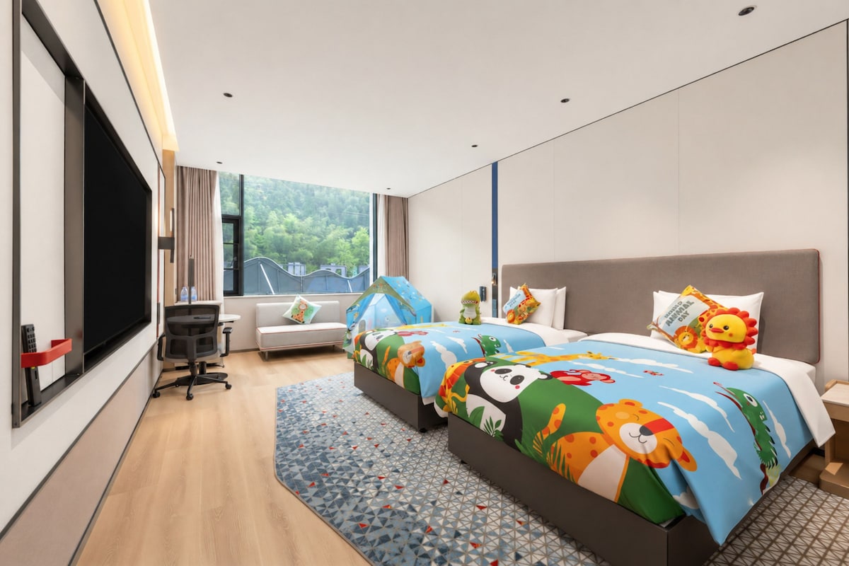 A modern hotel room with a large bed, a desk, a chair, and a TV.