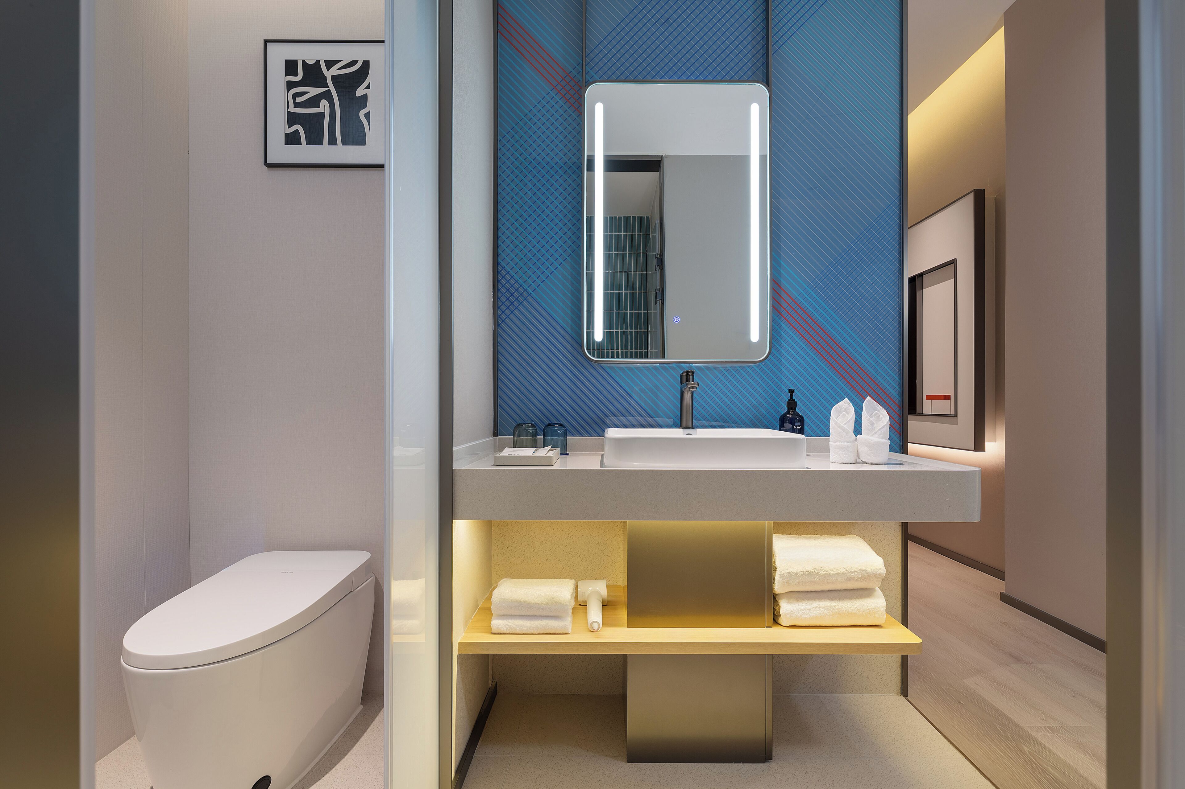 Un baño moderno con inodoro, lavamanos y espejo.