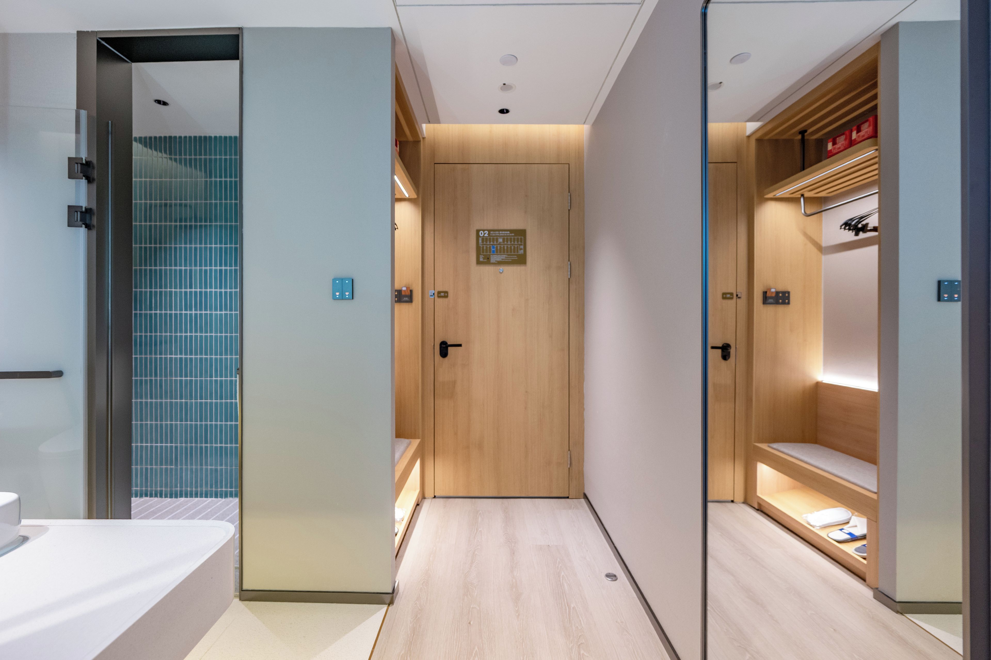 A modern bathroom with a shower, a toilet, and a sink. There is a wooden door with a sign above it.