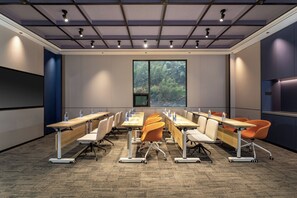 A conference room with a long table, chairs, and a large window with a forest view.