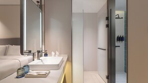 Une salle de bain moderne avec un grand miroir, un lavabo et un espace douche.