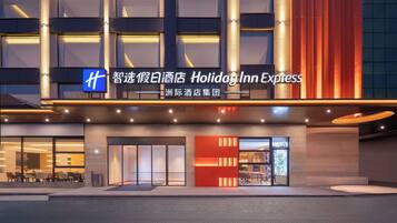Exterior moderno de un hotel con el letrero Holiday Inn Express, amplias ventanas y una entrada bien iluminada.