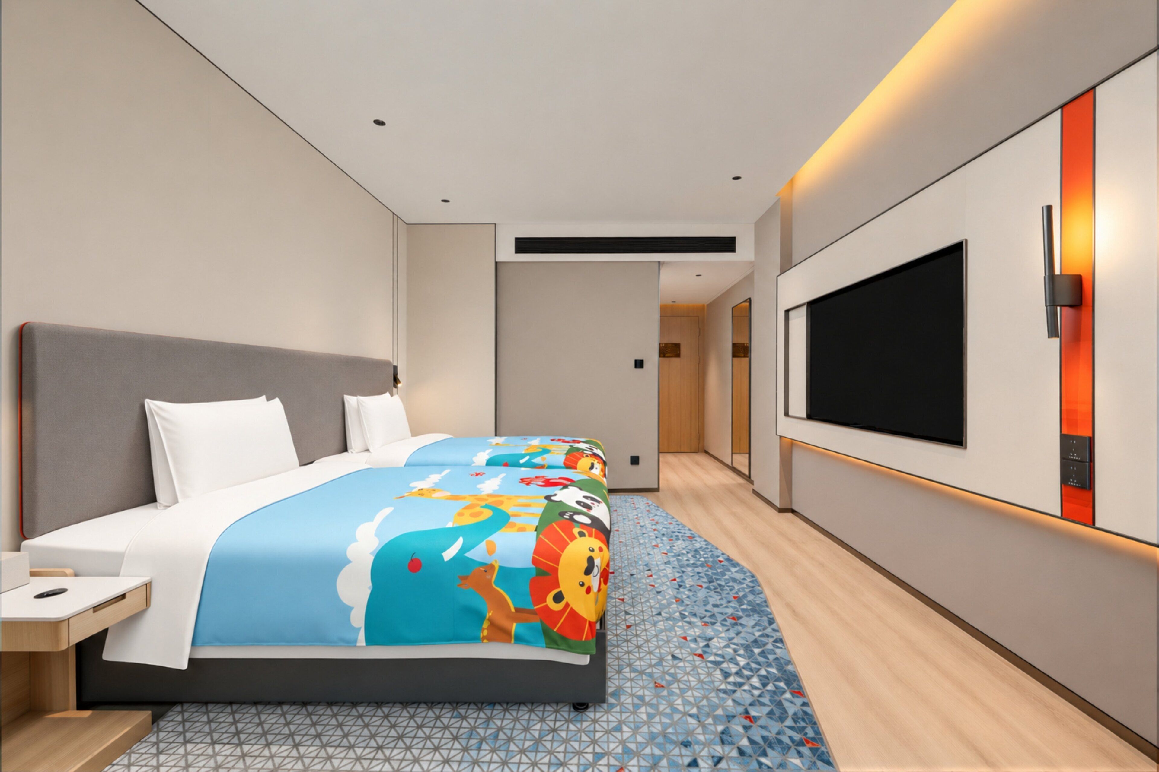 A modern hotel room with a large bed, a TV mounted on the wall, and a small desk.