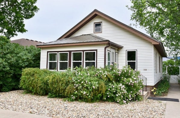 A single-story house with a gabled roof, white siding, and a small front porch.