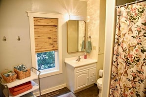 A bathroom with a window, a sink, a mirror, and a shower curtain.