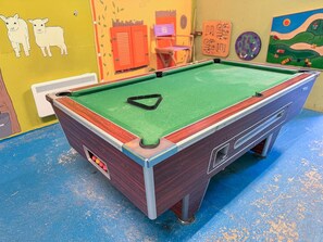 Ein Billardtisch mit grüner Spielbahn, umgeben von einem blauen Boden.