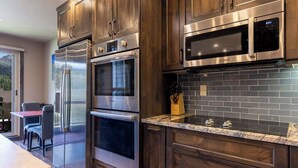 Una cocina con electrodomésticos de acero inoxidable, gabinetes de madera oscura y salpicadero de azulejos.