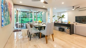 A modern living room with a dining area, large windows, ceiling fans, and a television. - Deluxe Modern Condo, with Cenote on Site.
24/7 security
5' walk to beach (Playa del Carmen)