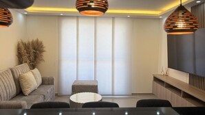 Un salon moderne avec un canapé, une table basse et des luminaires suspendus.