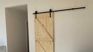Un salon moderne avec une porte coulissante de style grange, un canapé gris foncé et un plancher en bois.
