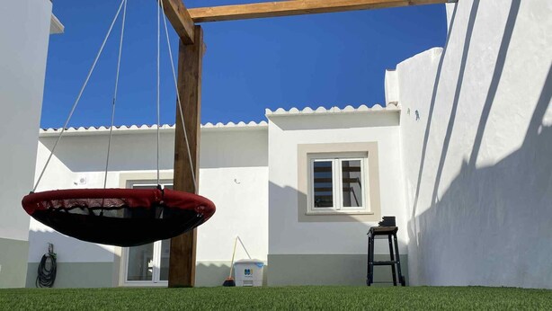 Un espace patio avec un fauteuil suspendu, une échelle et une fenêtre.