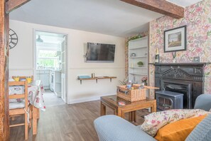 Ein Wohnzimmer mit Kamin, Fernseher und Essbereich mit Tisch und Stühlen.