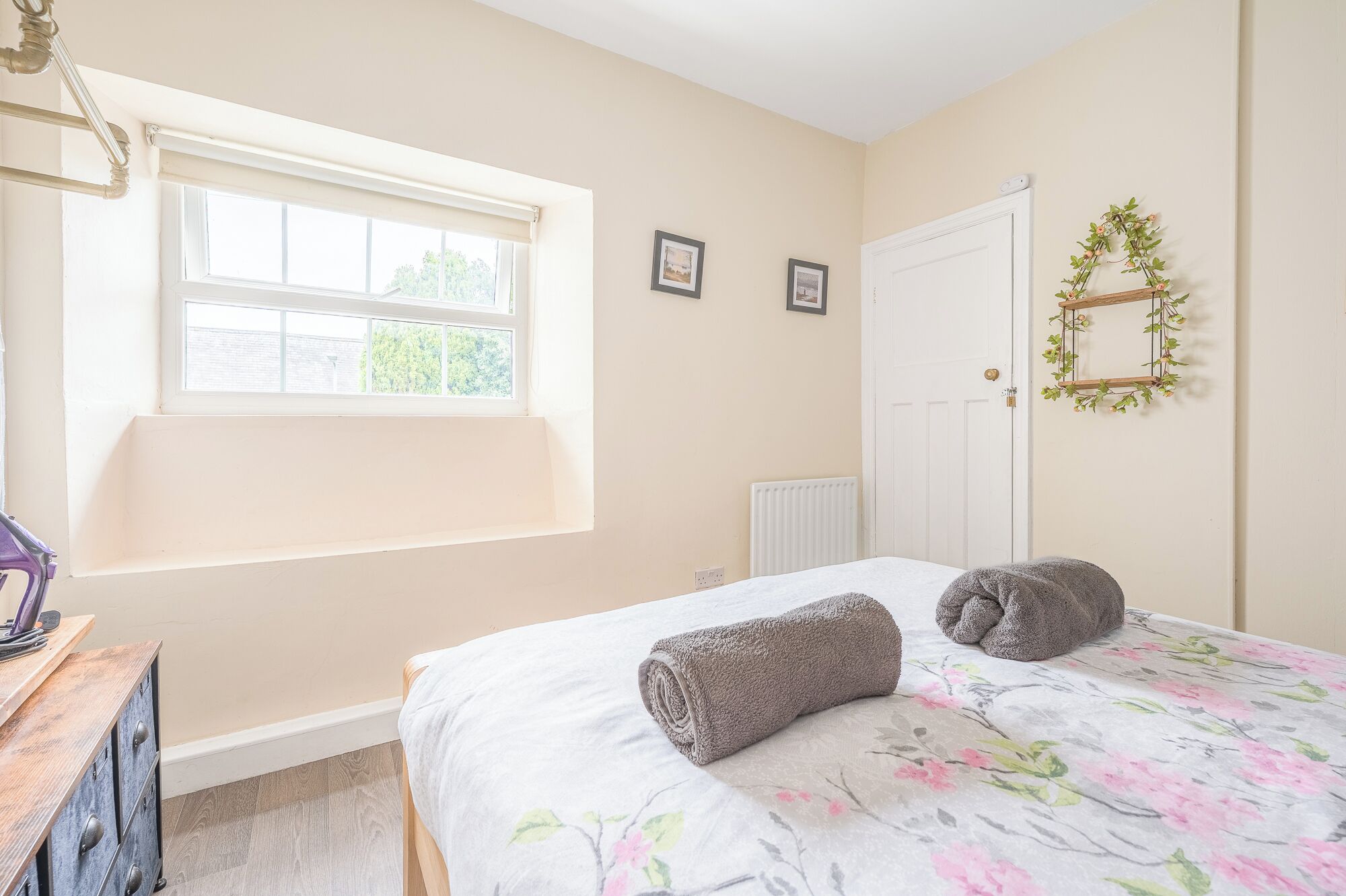 A bedroom with a bed, a window, a radiator, and a door.