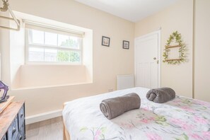 A bedroom with a bed, a window, a radiator, and a door. - Cosy 18th-Century Lake District Retreat with Charm & Comfort (Little Broughton)