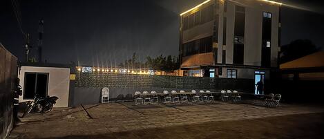 Een gebouw met een plat dak en een balkon met stoelen en tafels.