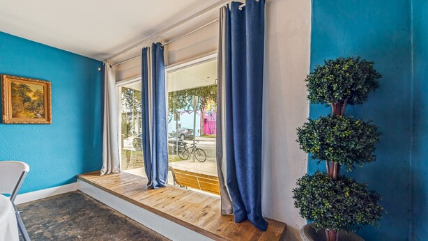 Una habitación con un banco de madera, una planta en maceta y vistas a la calle.