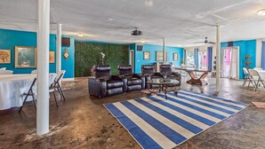 Amplia habitación con pared azul, alfombra a rayas, sofás de cuero y un proyector en el techo.