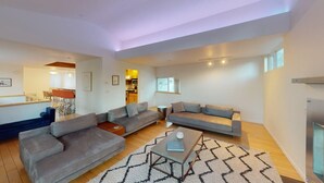 A modern living room with a sofa set, a coffee table, and a dining area visible in the background.
