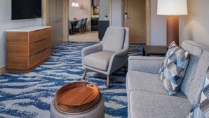 A hotel room with a wooden dresser, a grey armchair, a sofa with a patterned throw, a wooden side table, and a lamp. - Ski-in/out Marriott Mountain Valley Breckenridge sleeps 8 heated pool/hot tubs+ (Breckenridge)