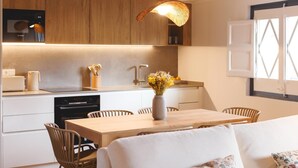 Eine moderne Küche mit Holzschränken, einem Geschirrspüler von Bosch und einem Essbereich mit Tisch und Stühlen.