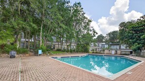 Una piscina rectangular con borde de azulejos, rodeada por un patio de ladrillo.
