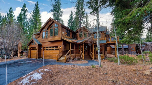Une grande cabane en bois dotée de plusieurs portes de garage, d’un porche couvert et d’un escalier menant à l’entrée.