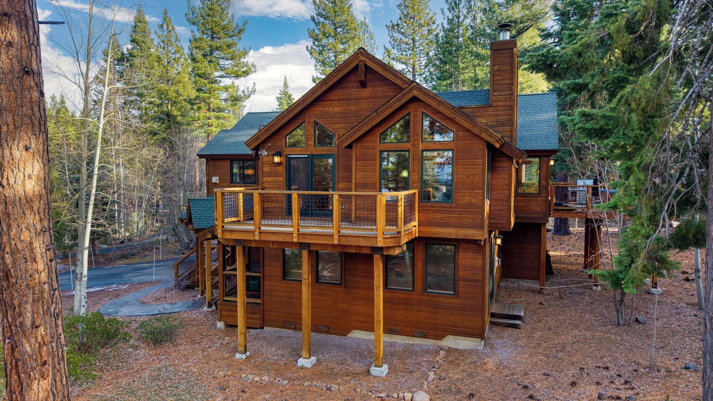 A wooden cabin with a balcony, surrounded by trees.