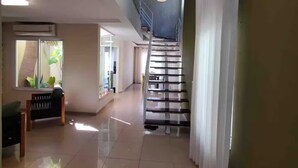 En rymlig hall med en trappa, en bänk och en hängande lampa.