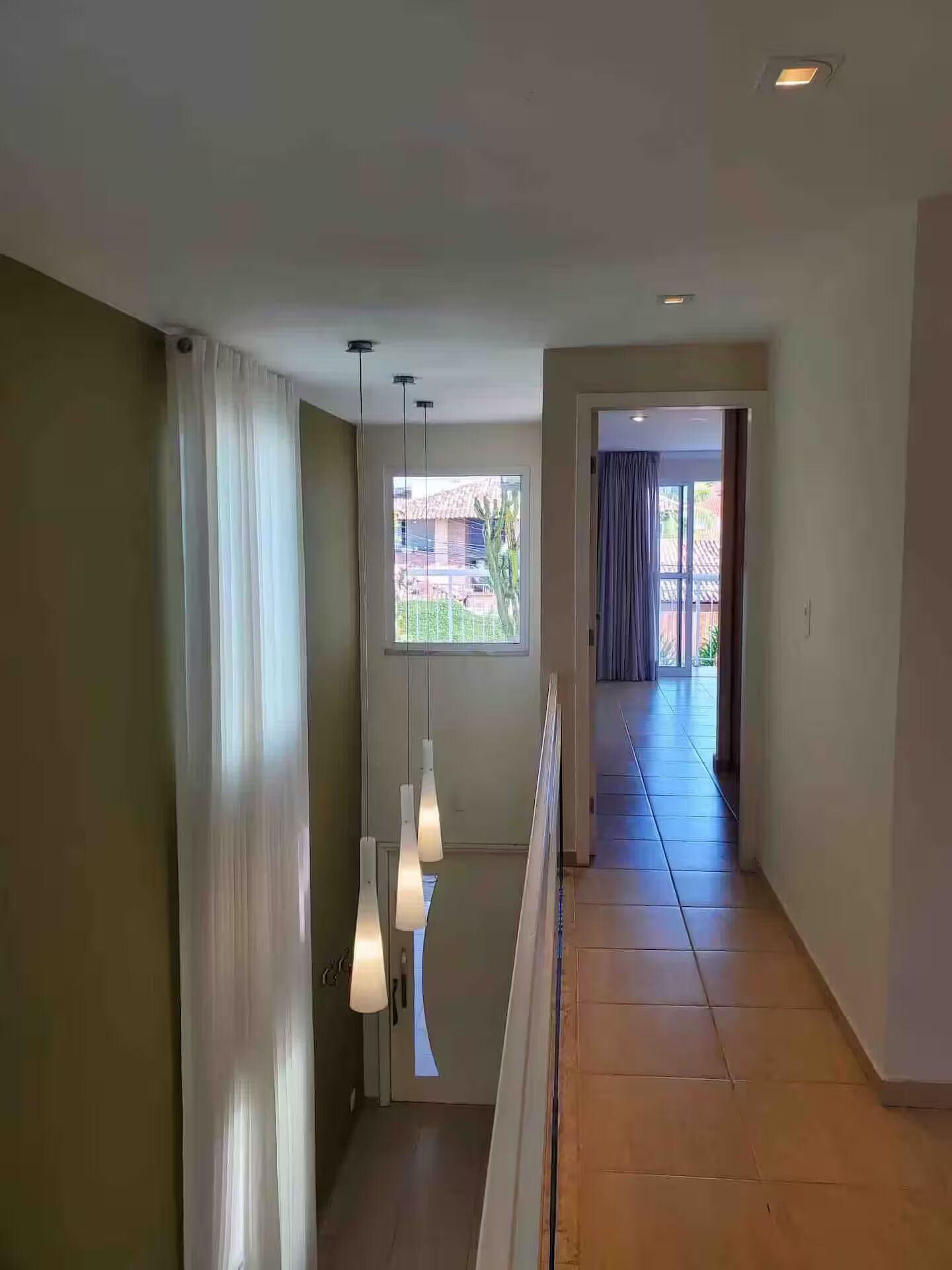 Un pasillo con vistas a un balcón, una ventana y una puerta que da a un espacio exterior.