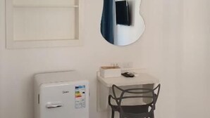 Una pequeña kitchenette con refrigerador, microondas y basurero.