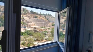 Una habitación con un amplio ventanal que da a un sitio histórico con ruinas y árboles.