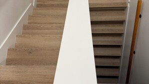 Eine Holztreppe mit weißen Trittstufen und einem Geländer.