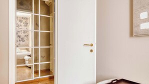 Ein Zimmer mit Holzboden, einer weißen Tür mit goldener Klinke und einer kleinen Holztablett auf einer weißen Oberfläche.