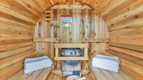 A sauna room with wooden walls, a bench, a bench seat, a heater, and towels. - Lake House Escape | Fire Pit+Jacuzzi+Sauna+Games (Tobyhanna)