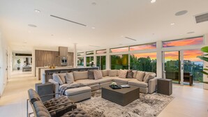 A modern living room with a sectional sofa, a coffee table, and a view of the outdoors through large windows. - Beverly Hills Private Modern Escape (Beverly Hills)