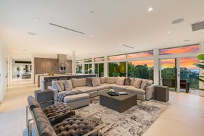A modern living room with a sectional sofa, a coffee table, and a view of the outdoors through large windows. - Beverly Hills Private Modern Escape (Beverly Hills)