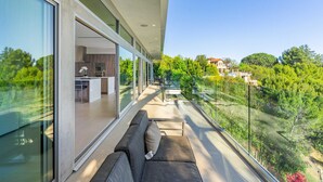 A modern balcony with a glass railing overlooking a lush garden and a residential area. - Beverly Hills Private Modern Escape (Beverly Hills)