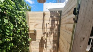 Una terraza de madera con zona de ducha integrada, rodeada de follaje.