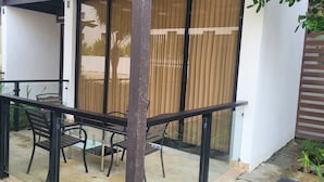 Ein Balkon mit Glastür, einem Metalltisch und Stühlen.
