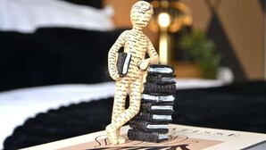 Une sculpture représentant une figure tenant des livres sur une table.